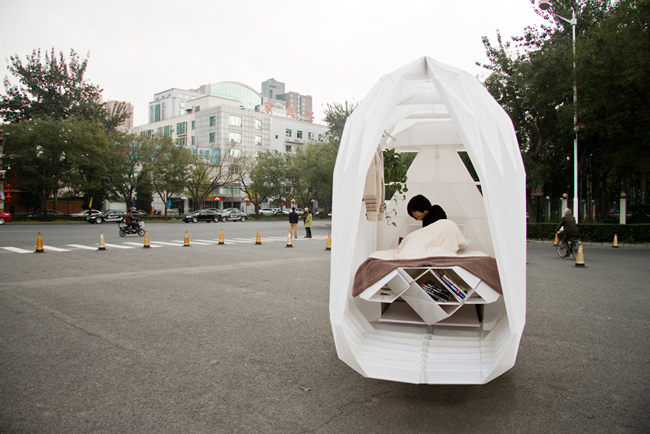 Una casa movil sobre un triciclo hecha con planchas de plástico 
